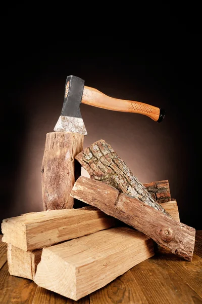 Firewood and axe on floor on dark background — Stock Photo, Image