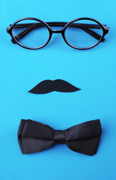 Brýle, knír a motýlek tvořící tvář na barvu pozadí — Stock fotografie