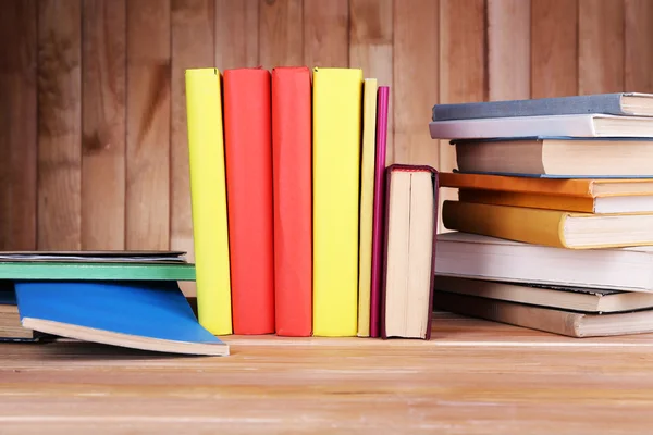 Buku-buku di meja kayu dengan latar belakang dinding kayu — Stok Foto