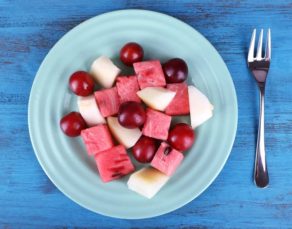 Tranches de melon, de prune et de pastèque en assiette sur fond de bois — Photo