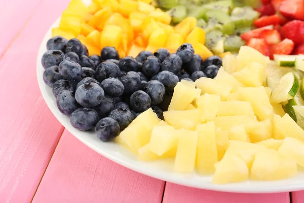 Frutas en rodajas en plato sobre mesa de madera — Foto de Stock