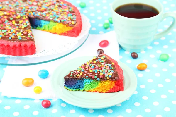 Heerlijke regenboogcake op plaat, op tafellaken achtergrond — Stockfoto