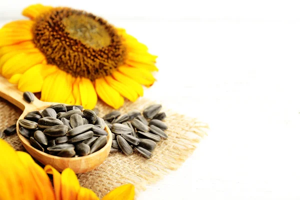 Sunflowers and seeds on wooden background — Stock Photo, Image