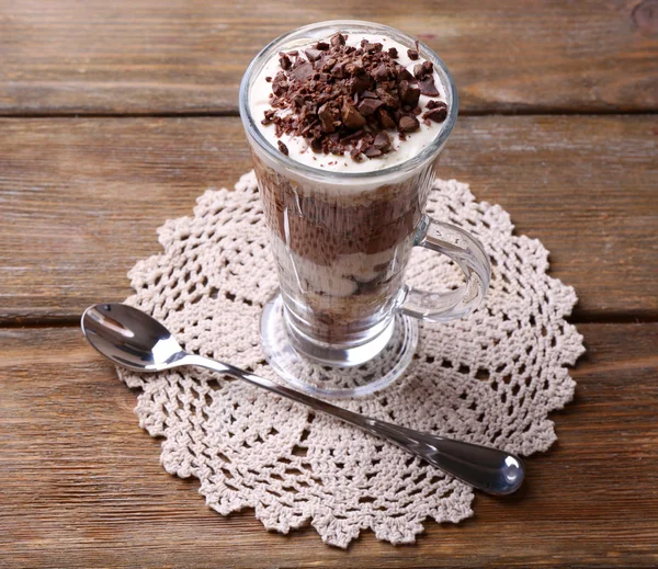 Yogurt, dengan krim cokelat, coklat cincang dan muesli disajikan dalam gelas di latar belakang kayu — Stok Foto