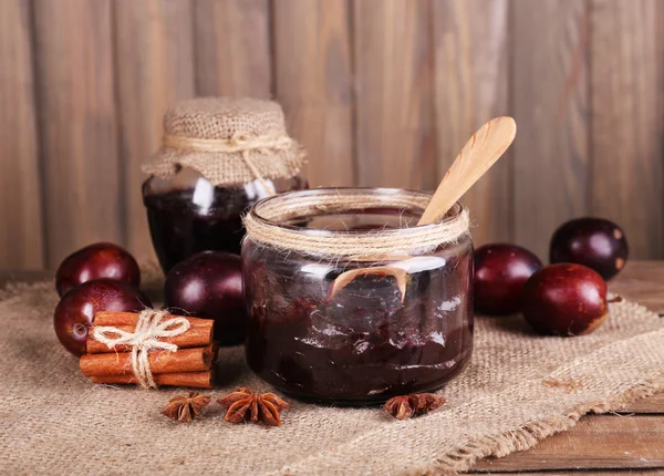 Confiture de prunes savoureuse dans des bocaux et des prunes sur table en bois sur fond en bois — Photo
