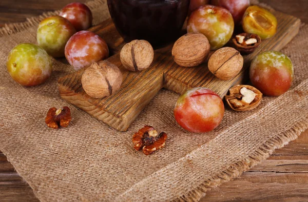 Marmellata di prugne saporita in vaso e prugne su tavolo di legno primo piano — Foto Stock