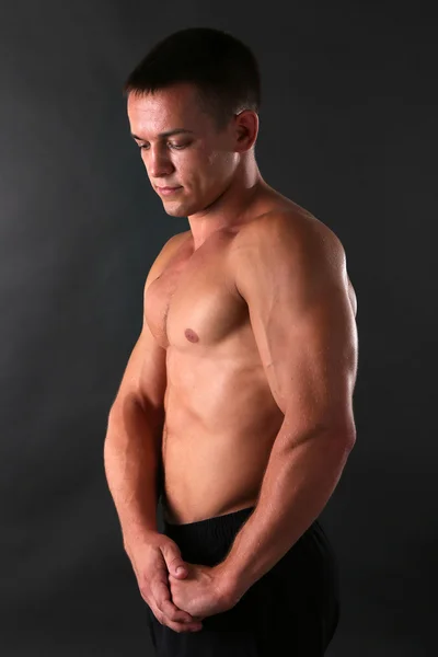 Bello muscolare giovane uomo su sfondo scuro — Foto Stock