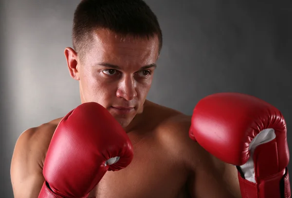 Bello giovane sportivo muscoloso con guanti da boxe su sfondo scuro — Foto Stock