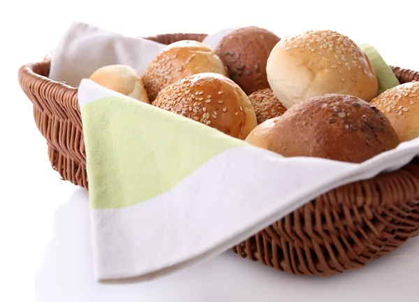 Tasty buns with sesame in wicker basket, isolated on white — Stock Photo, Image