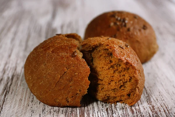 Smakelijke bruine broodjes op een houten achtergrond kleur — Stockfoto