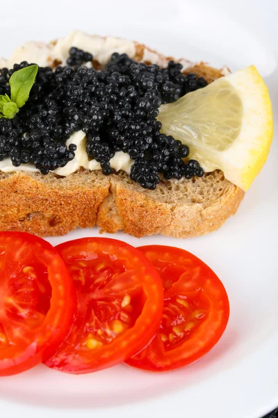 Caviar negro y mantequilla en pan con tomates en primer plano —  Fotos de Stock