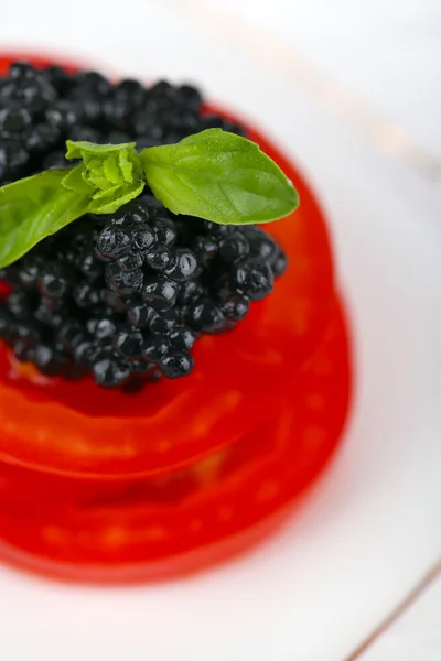 Tomatenscheiben mit schwarzem Kaviar auf Teller Nahaufnahme — Stockfoto