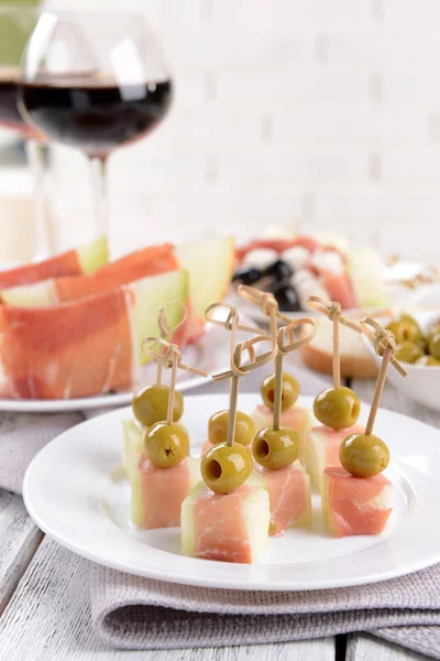 Delicious melon with prosciutto on plate on table on light background — Stock Photo, Image