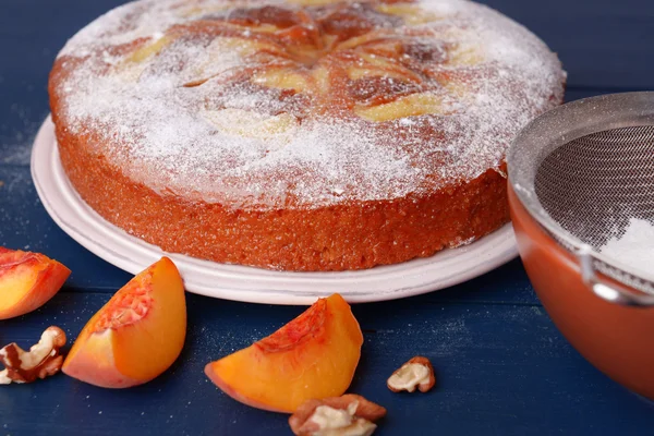 Delicious cake with peach and nuts on wooden table — Stock Photo, Image