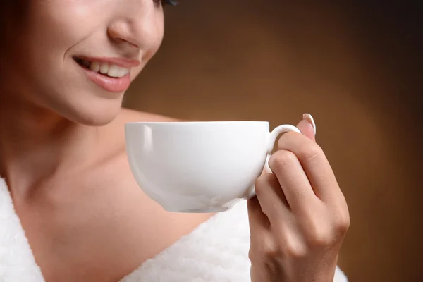 Bella ragazza con una tazza di caffè su sfondo marrone — Foto Stock