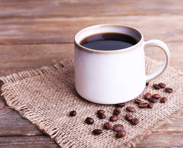 Taza de café sobre tela de saco sobre fondo de madera — Foto de Stock