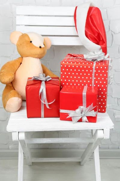 Tuğla duvar zemin üzerine beyaz koltuk üzerinde Noel hediyeleri — Stok fotoğraf