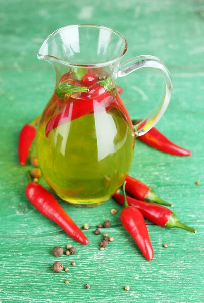 Huile d'olive naturelle infusée maison avec des piments rouges sur fond de bois de couleur — Photo