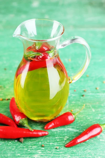 Hemmagjord naturlig infunderas olja med röd chilipeppar på färg trä bakgrund — Stockfoto