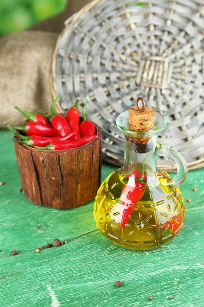 Homemade natural infused olive oil with red chili peppers in bottle on color wooden table, on bright background — Stock Photo, Image