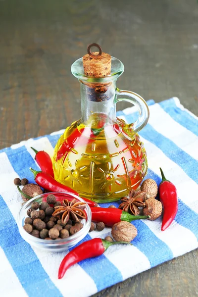 Zelfgemaakte natuurlijke doordrenkt olijfolie met rode chilipepertjes en specerijen in glazen fles op houten achtergrond — Stockfoto