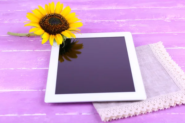 Tablet e girassol em guardanapo em fundo de madeira — Fotografia de Stock