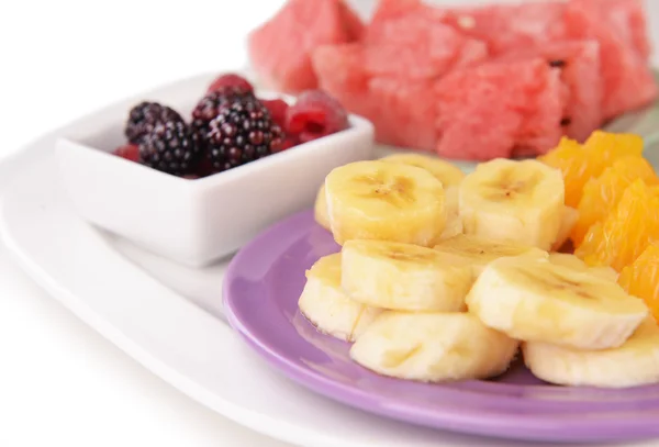 Slices of fruits with berries on plate close up — Stock Photo, Image