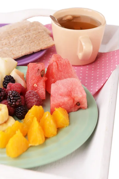 Rebanadas de frutas con pan crujiente en el plato y taza de té en bandeja de madera de cerca — Foto de Stock