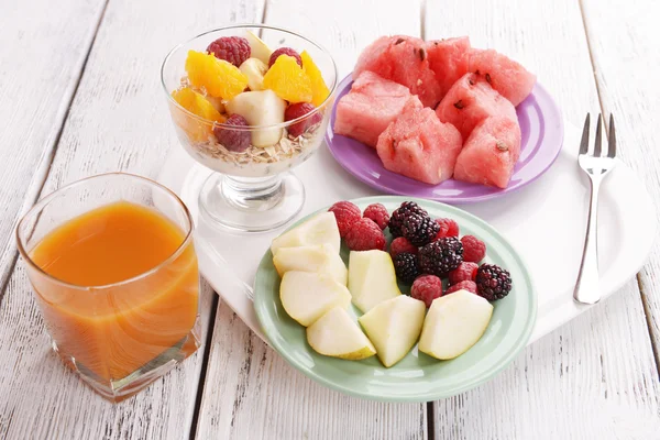 Slices of fruits with berries and muesli on wooden table — Stock Photo, Image