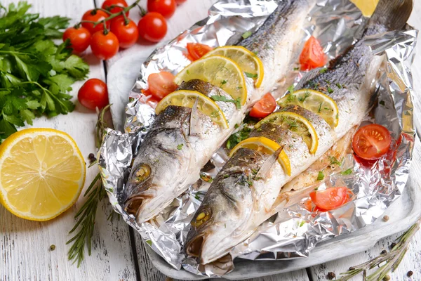 Pesce al forno saporito in lamina di metallo su tavolo primo piano — Foto Stock