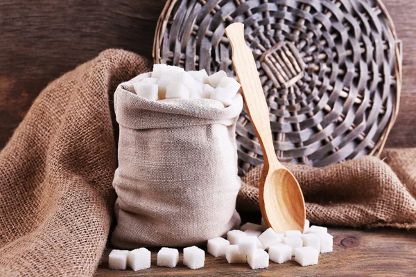 Açúcar refinado no saco em fundo de madeira — Fotografia de Stock
