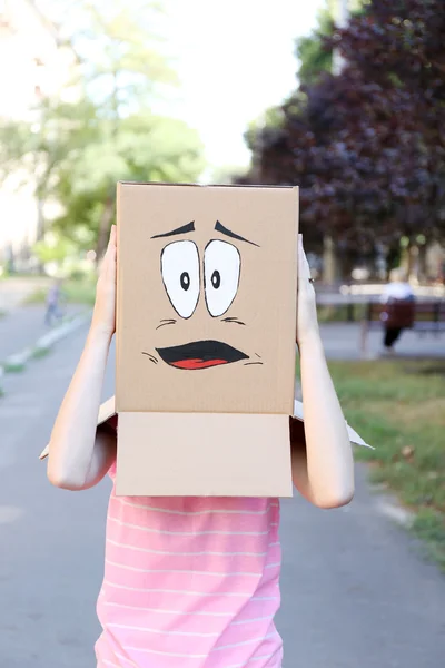 Woman with cardboard box on her head with sad face, outdoors — Stock Photo, Image