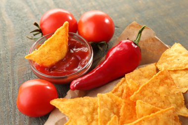 lezzetli cips, kırmızı domates ve biber kağıt, ahşap zemin üzerinde