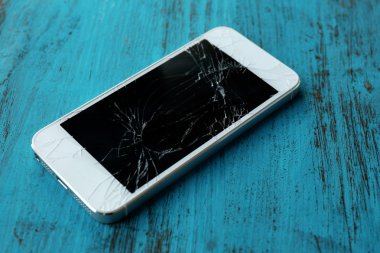 Ahşap arka planda kırık ekranlı modern cep telefonu