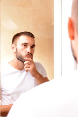 Genç adam sakalını kesiyor.