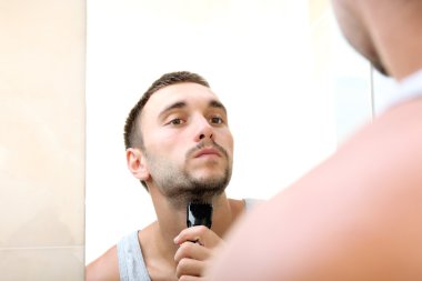 Genç adam sakalını kesiyor.