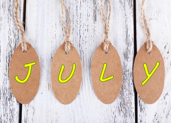 July tags on wooden background — Stock Photo, Image