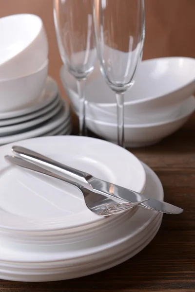 Set di piatti bianchi sul tavolo su sfondo marrone — Foto Stock