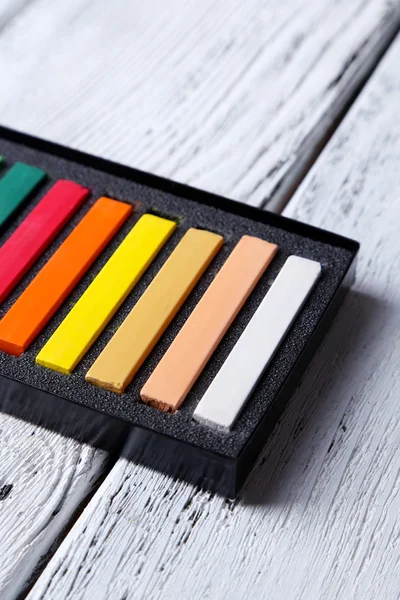 Pasteles de tiza de colores en caja sobre fondo de madera — Foto de Stock