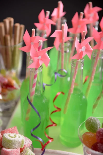 Bouteilles de boisson avec de la paille et des bonbons sur fond sombre — Photo