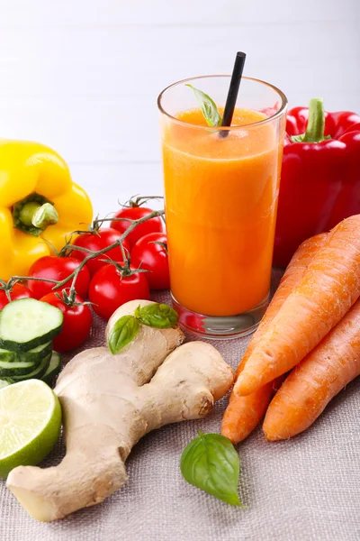 新鲜的胡萝卜汁和蔬菜在桌布上的玻璃 — 图库照片