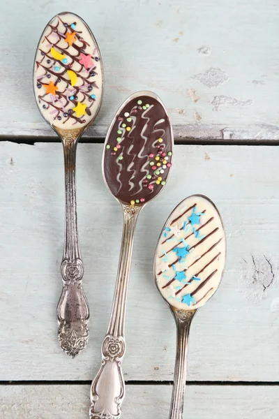 Spoons with tasty chocolate for party on old wooden table — Stock Photo, Image