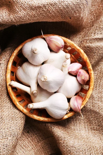 Fresh garlic in wicker basket, on wooden background — Stock Photo, Image