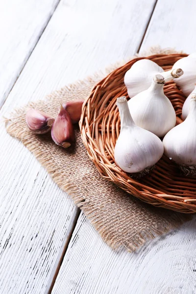 Fresh garlic on wicker mat, on wooden background — Stock Photo, Image