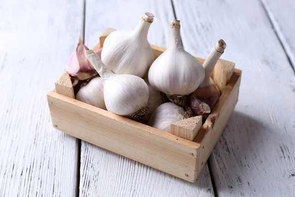 Fresh garlic in box, on wooden background — Stock Photo, Image