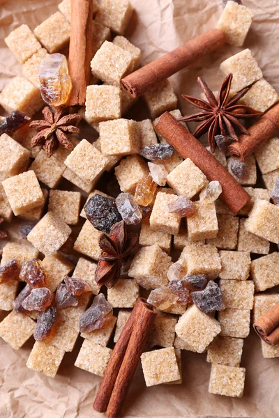 Brown sugar cubes and spices on paper background — Stock Photo, Image