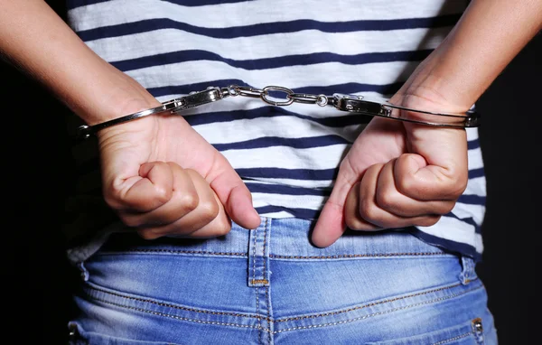 Злочинні руки замкнені в наручниках на темному тлі — стокове фото