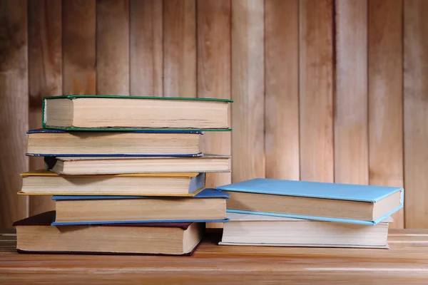 Books on wooden table on wooden wall background — Stock Photo, Image