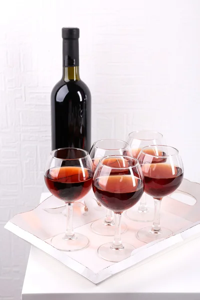 Glasses and wine bottle on tray in room — Stock Photo, Image