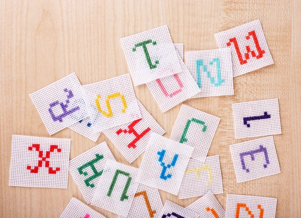 Handmade embroidered letters on white fabric, on wooden background — Stock Photo, Image